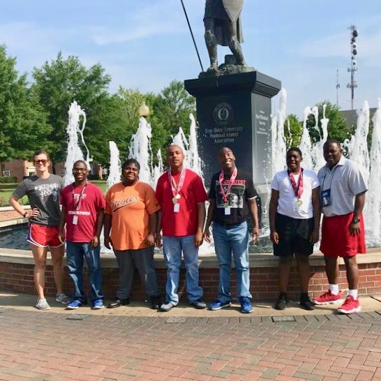  Five student athletes stand with two of their coaches